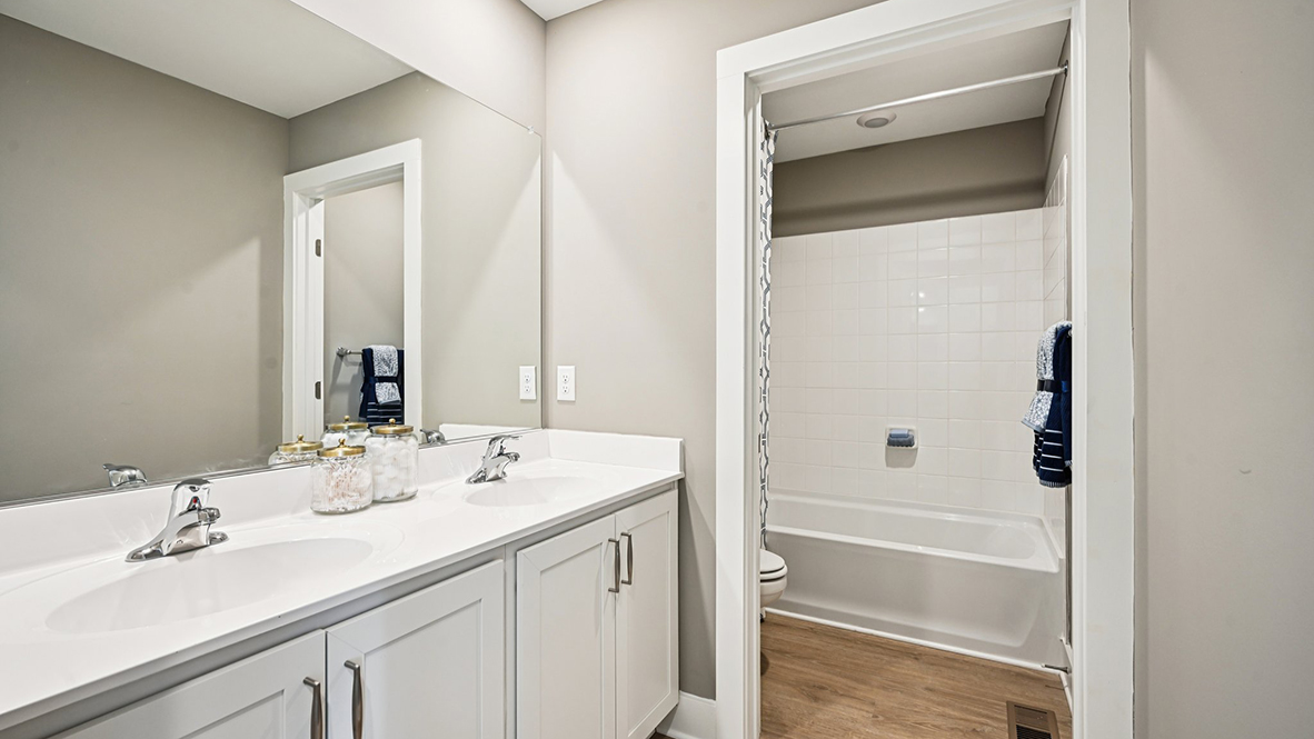 The bathroom has a double bowl vanity with tub shower.
