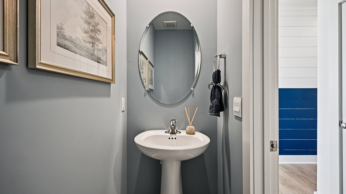 The powder room is located in the hallway leading to the two-car garage.