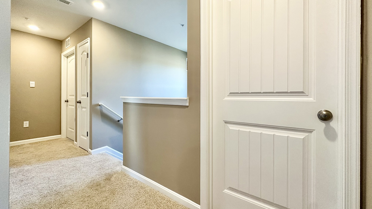 The stairwell opens to a spacious upstairs hallway.