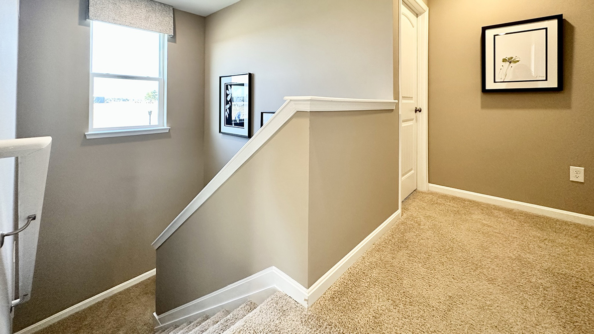 The stairwell opens to a spacious upstairs hallway.