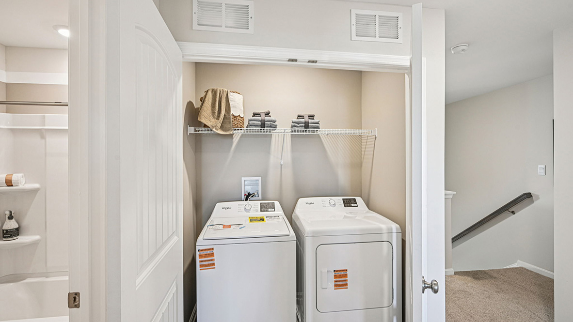 A functional upstairs laundry closet comes complete with a full-size washer and dryer.