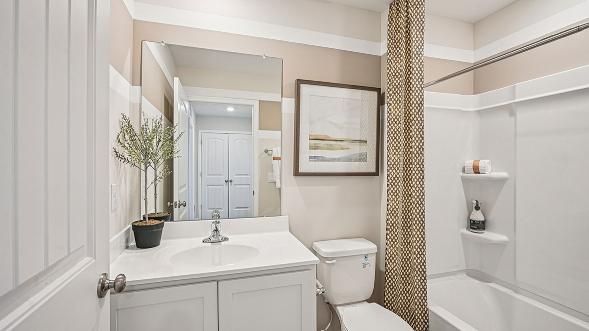 A guest bathroom with a vanity and tub shower is located down the hallway.