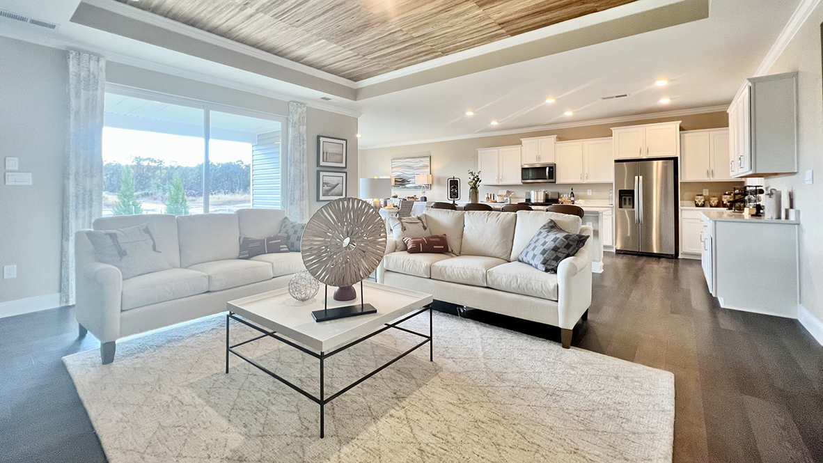 The open-concept great room with a tray ceiling leads you to the covered porch.