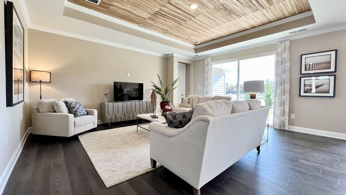 The open-concept great room with a tray ceiling leads you to the covered porch and primary bedroom.