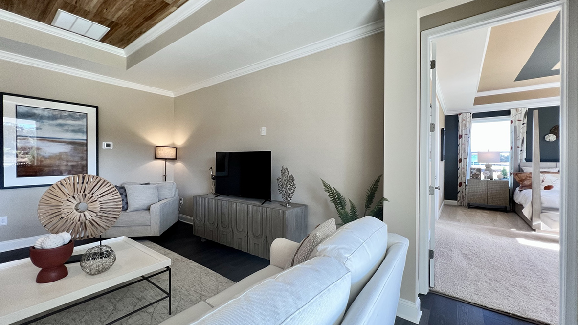 The open-concept great room with a tray ceiling leads you to the primary bedroom.