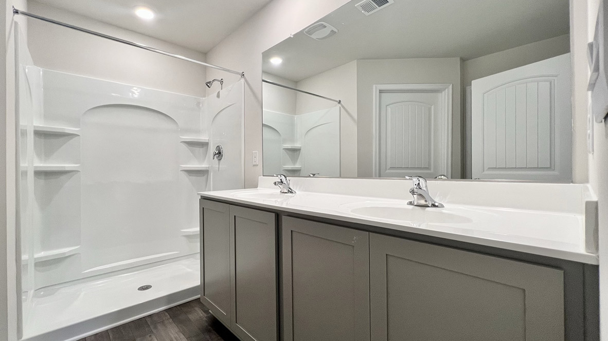 The oversized owner’s bathroom with a double vanity, a walk-in shower and a toilet closet.