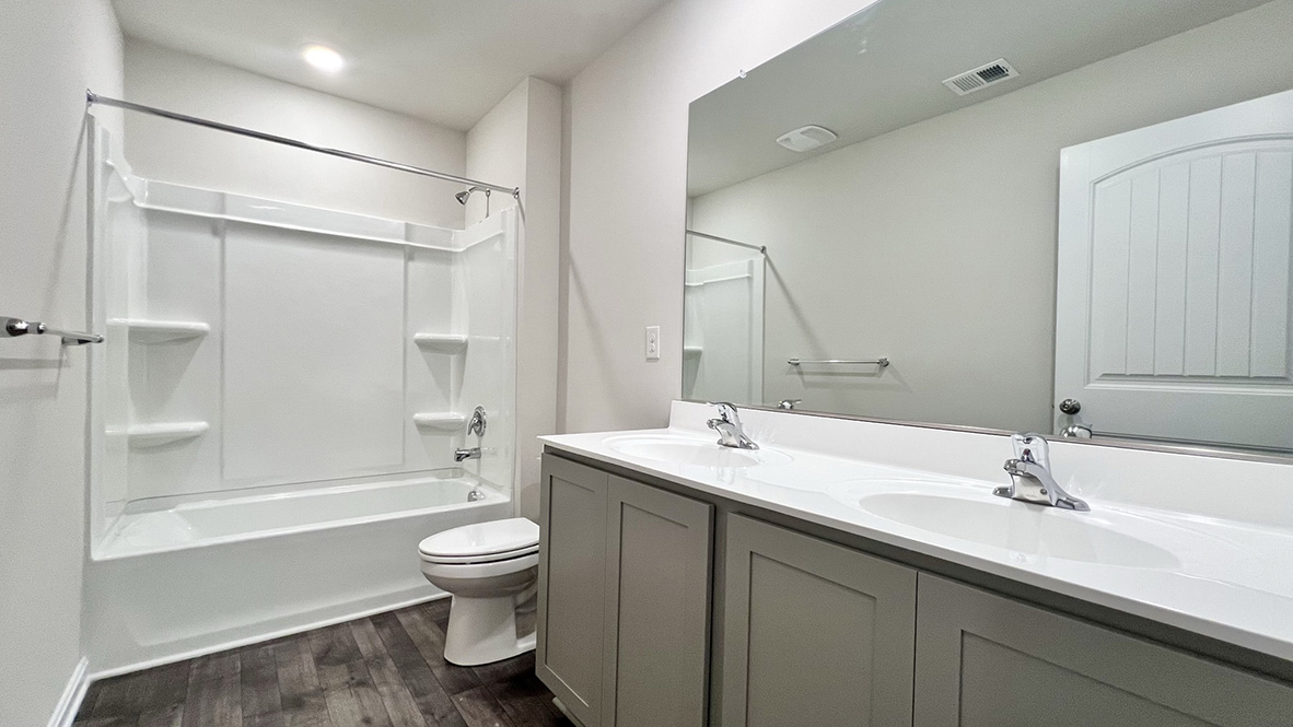 The secondary bathroom with a double-bowl vanity and tub.
