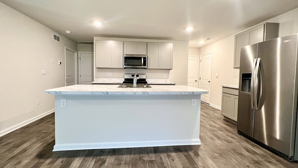The spacious kitchen showcases a large island with a sink.