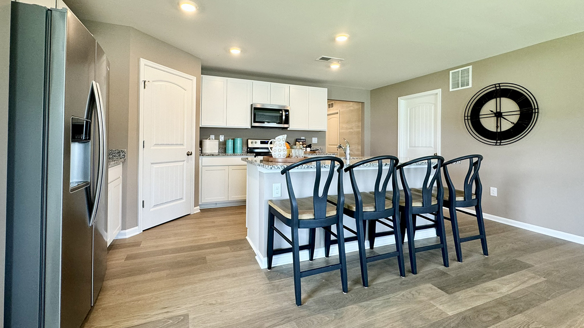 A large kitchen island with a sink is centered in the kitchen.