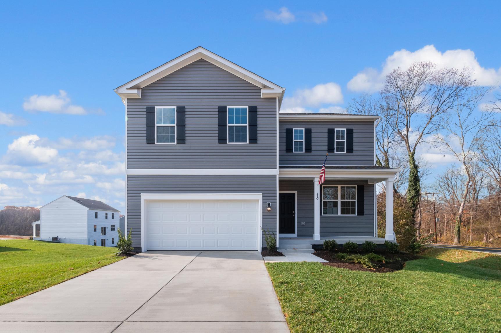 Two-Story Galen plan home with vertical plank siding, two-car garage, and covered porch with an American Flag