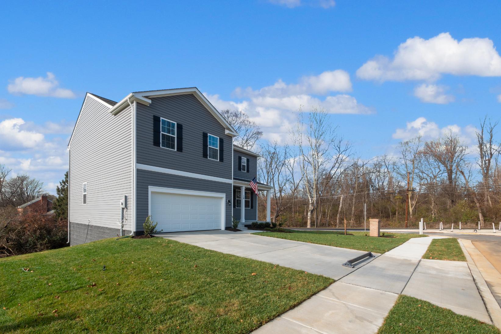 Alternate view of Two-Story Galen plan home with vertical plank siding, two-car garage, and covered porch with an American Flag
