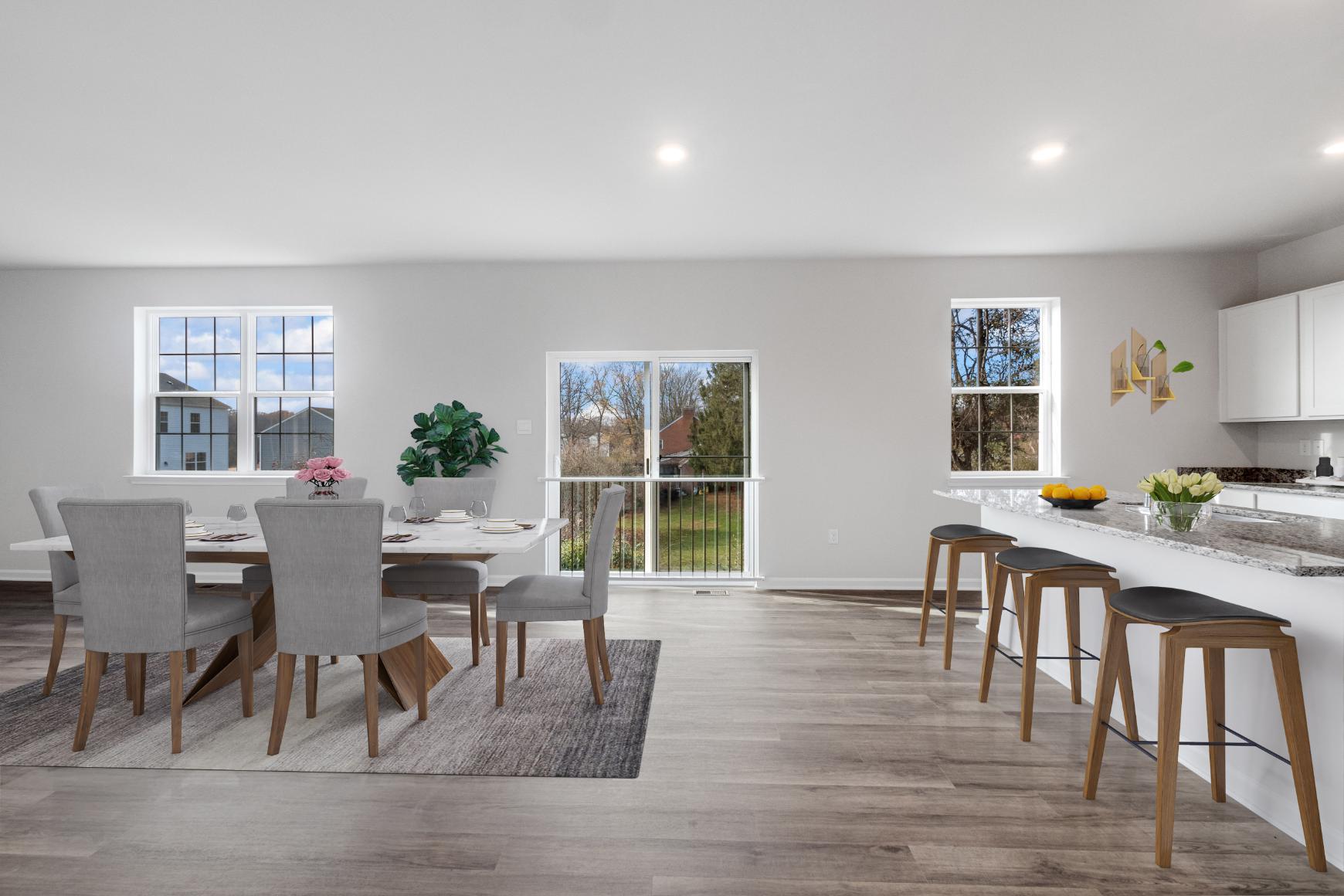 Galen plan kitchen with a bar, barstools, dining room table and chairs and three windows