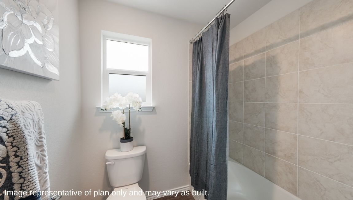Primary bathroom with combined shower and bathtub and window above toilet.