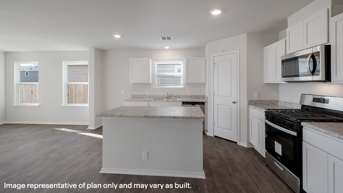 Spacious, open-concept kitchen flowing into dining area with hard surface flooring and patio door.