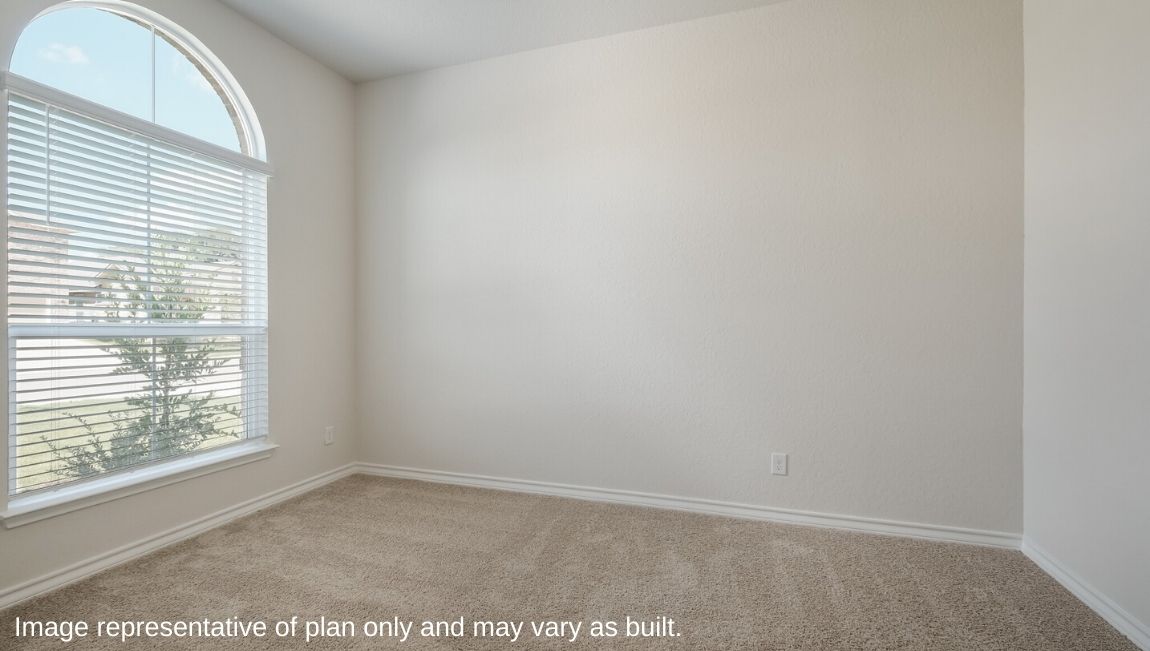 Secondary bedroom with arched window and carpet flooring.