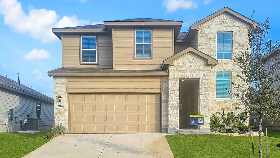 Two story home with light colored stone and clean landscaping.
