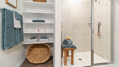 primary ensuite bathroom with built-in shelving and walk in shower with tile surround