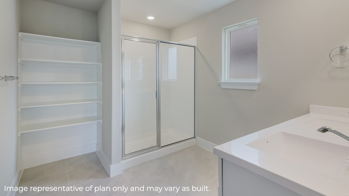 spacious primary bathroom with built in shelving, walk in shower and dual vanity sinks.