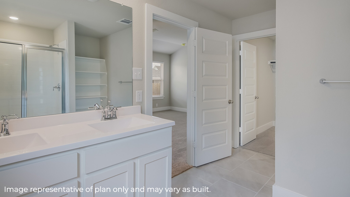 Spacious primary bathroom with dual vanity sinks, large walk in shower, built in shelving and spacious walk in closet.