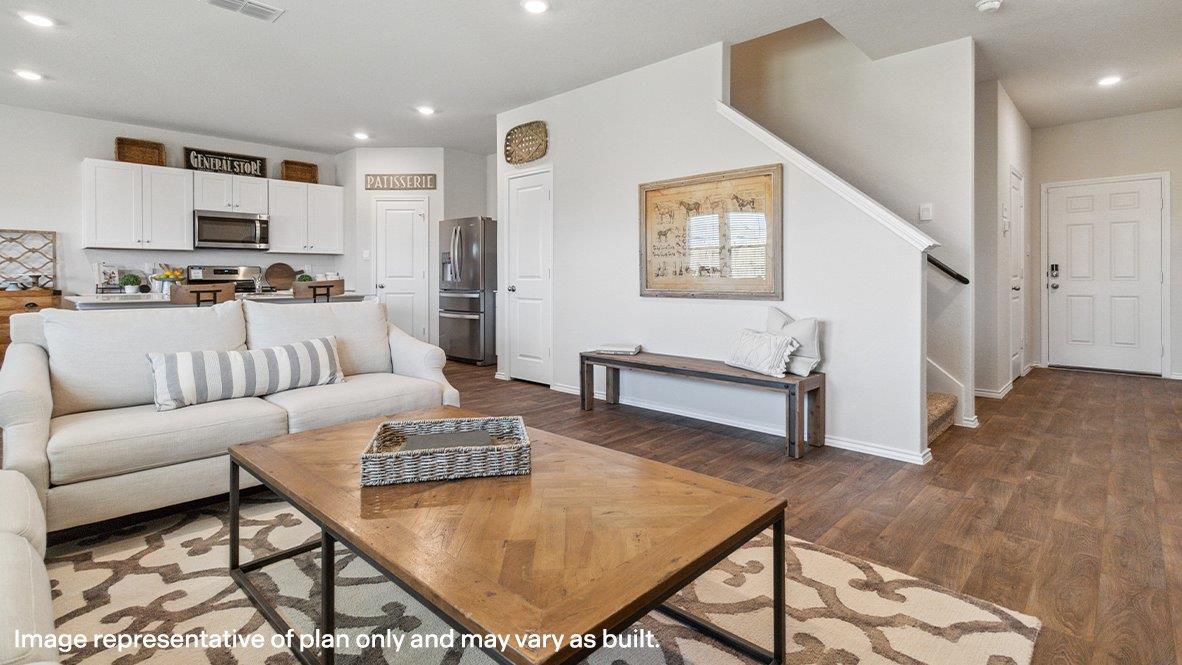 Entryway leading past staircase and flowing into the open concept living room and kitchen.