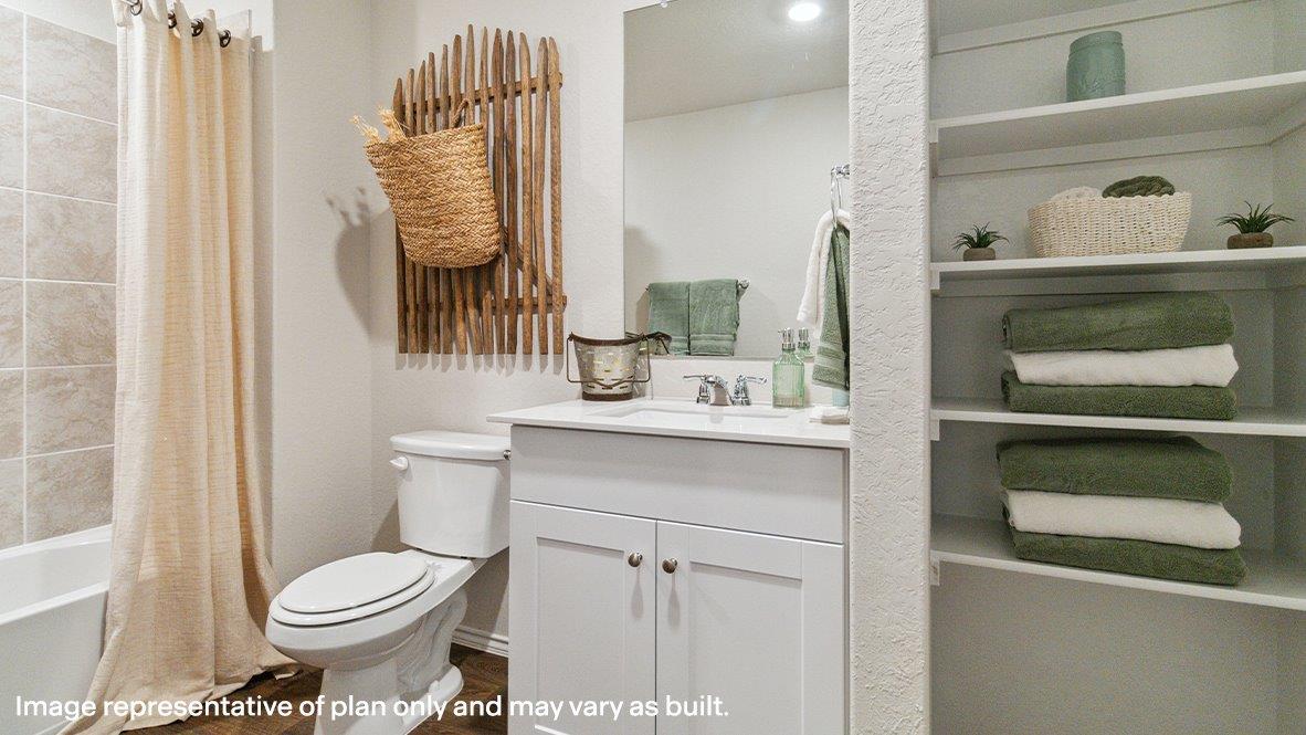 Second full bathroom with tub and shower combo, toilet, single vanity sink and built in shelving.