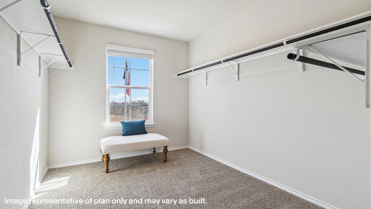 Grand primary walk in closet with quality carpet flooring, window and built in shelves.