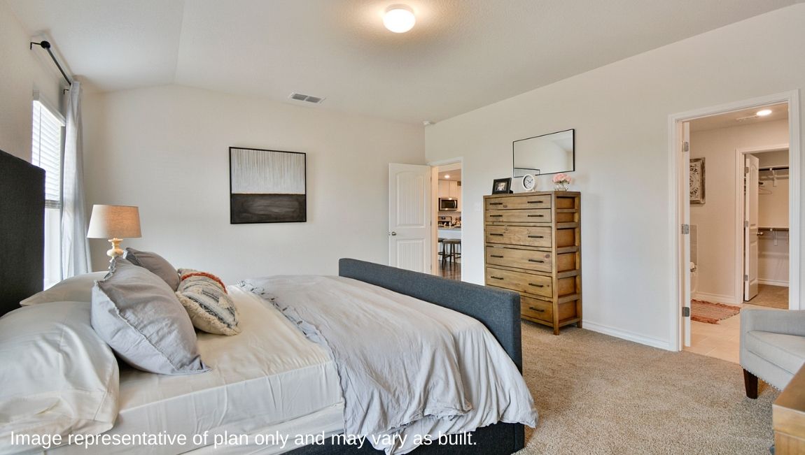 Spacious primary bedroom with quality carpet, semi-vaulted ceilings and doorway leading to ensuite bathroom