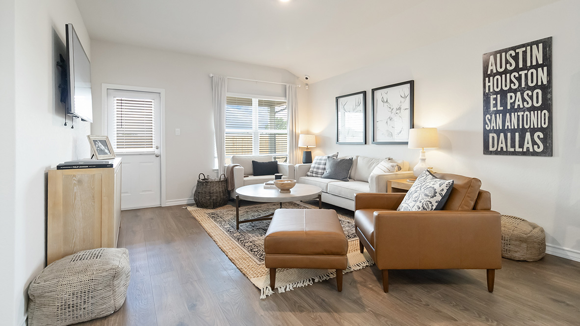 Open-concept family room with hard surface flooring, large windows, and door leading to back patio