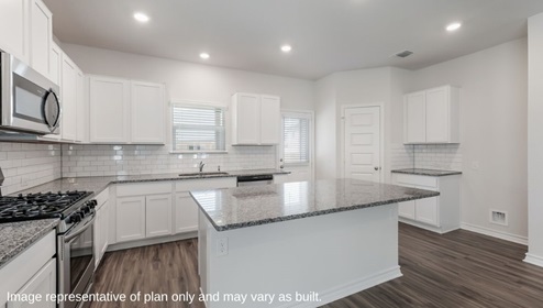 DR Horton Bulverde Copper Canyon the hondo floor plan 2702 square feet bright kitchen with white cabinetry stainless steel appliances large kitchen island granite countertops and kitchen window overlooking backyard