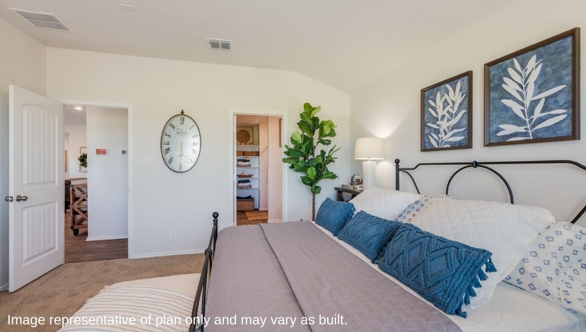 DR Horton San Antonio Laurel Vistas the caroline floor plan 1489 square feet main bedroom suite with carpet flooring, king sized bed and doorway leading to ensuite bathroom