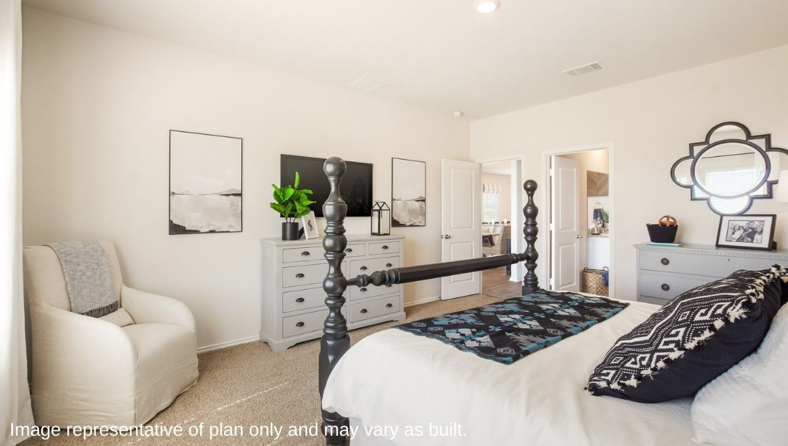 DR Horton San Antonio Laurel Vistas the jasmine floor plan 2182 square feet main bedroom suite with carpet flooring, dresser, armchair, and four poster king sized bed with doorway leading to main bedroom suite