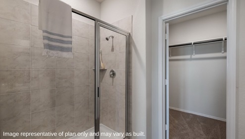 primary bathroom with walk in shower and closet with shelving