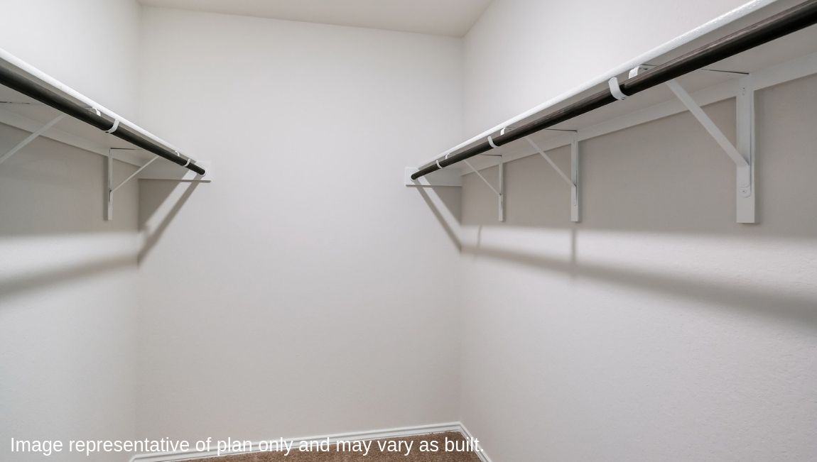 Spacious primary closet with shelving on either side.