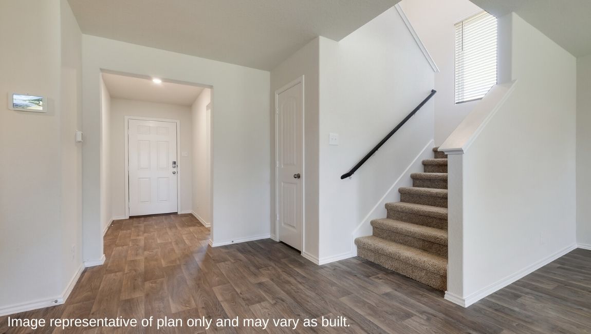 Foyer opening up to staircase and spacious kitchen.