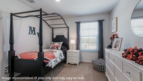 San Antonio Applewood New Construction Homes Express 1858 square feet The Florence children's bedroom with carpet flooring black twin sized canopy sleigh bed with white flowered comforter set and Medina Valley High School pillow and throw blanket white bedside table with table lamp black sheer window curtains black and white houndstooth bean bag white chest of drawers with round wall mirror cheerleader decor and framed wall art