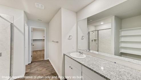 San Antonio Applewood New Construction Homes ensuite bathroom with plank flooring open air shelving white cabinets single vanity sink and spacious walk in closet