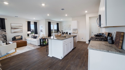 Open-concept kitchen, dining and living area with hard surface flooring and large windows.