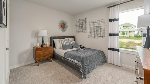 Midtown Model secondary bedroom with carpeted flooring and window.