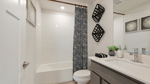 Midtown Model secondary bathroom with gray cabinetry and white countertops.