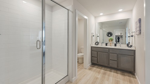 Midtown Model primary bathroom with vinyl plank flooring and tile surround shower.