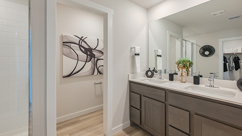 Midtown Model primary bathroom with double sink vanity and vinyl plank flooring.