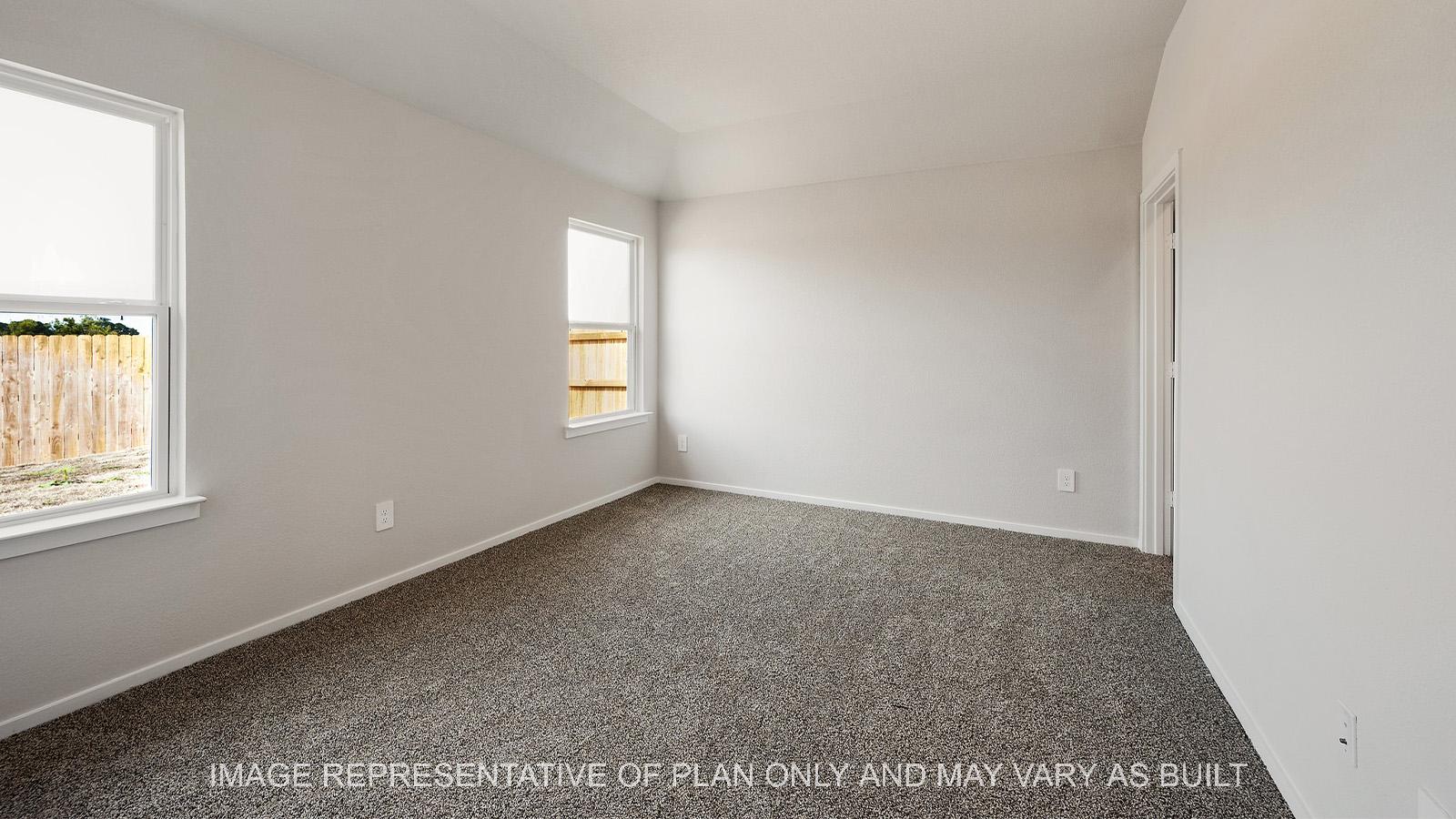 Amber primary bedroom with windows and carpeted flooring.