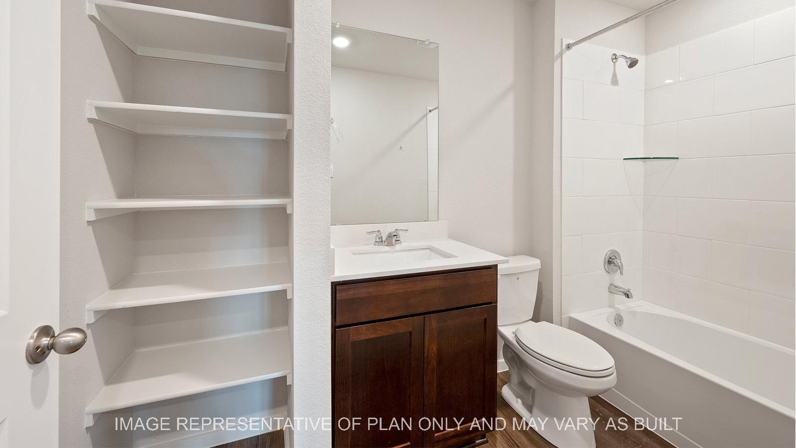 Caroline secondary bathroom with built-in shelving, quartz countertops, and ceramic tile shower/tub surround.