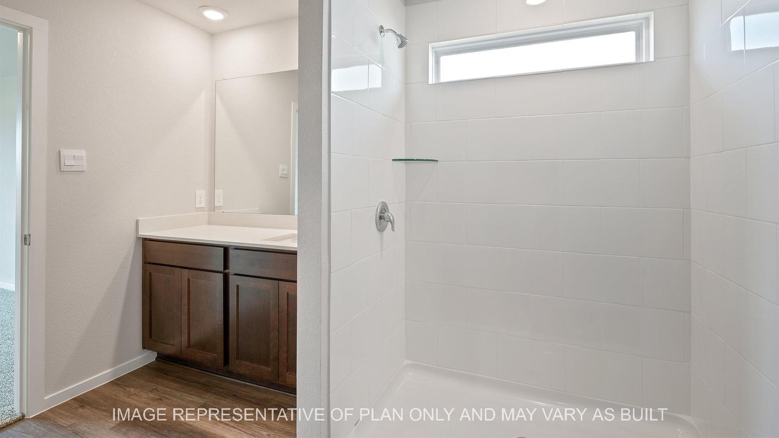 Caroline primary bathroom with vinyl plank flooring, quartz countertop vanity, and ceramic tile shower surround.