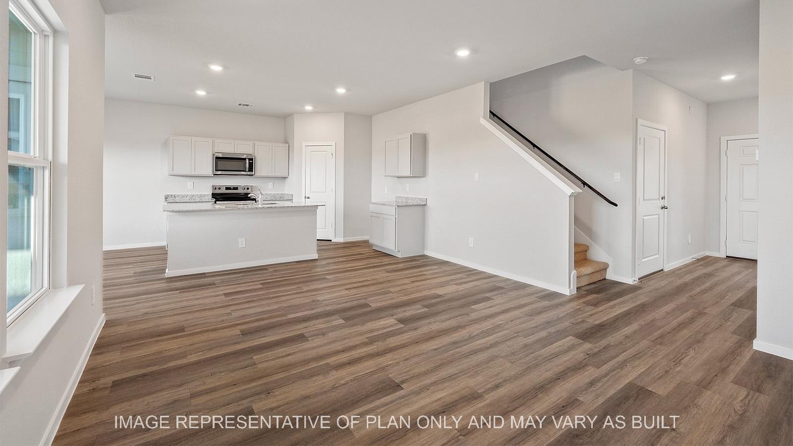 Emma open-concept living room with view to kitchen and staircase.