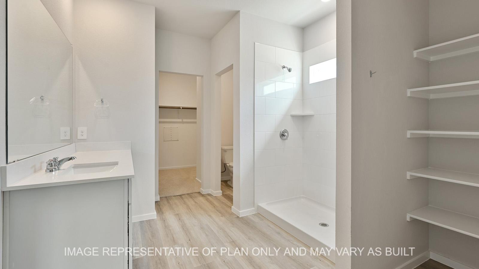 Jasmine primary bathroom with white cabinetry, granite countertops, linen shelving, ceramic tile shower surround, and vinyl plank flooring.