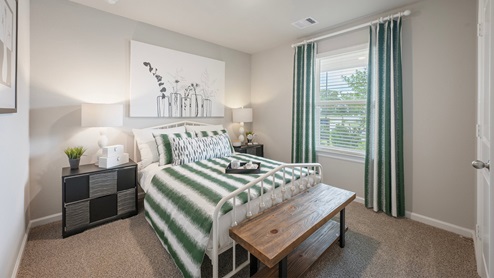 Pleasant Hill Model Home secondary bedroom with carpeted flooring and green accents.