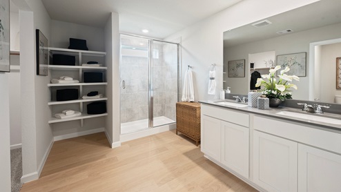Pleasant Hill Model Home primary bathroom with linen shelving, dual quarts vanity top, and walk-in shower.