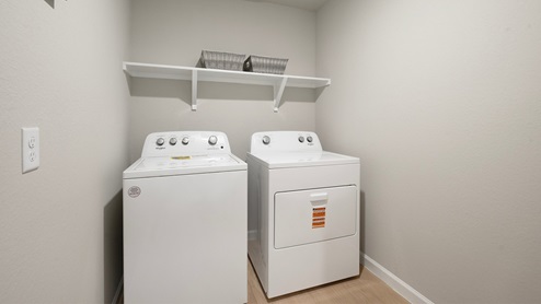 Pleasant Hill Model Home utility room with vinyl plank flooring and overhead shelf.