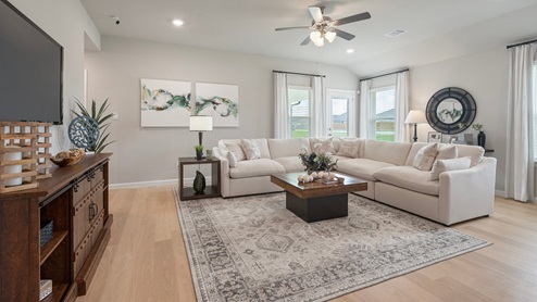 Pleasant Hill Model Home living room with large sectional and tv console with access to backyard.
